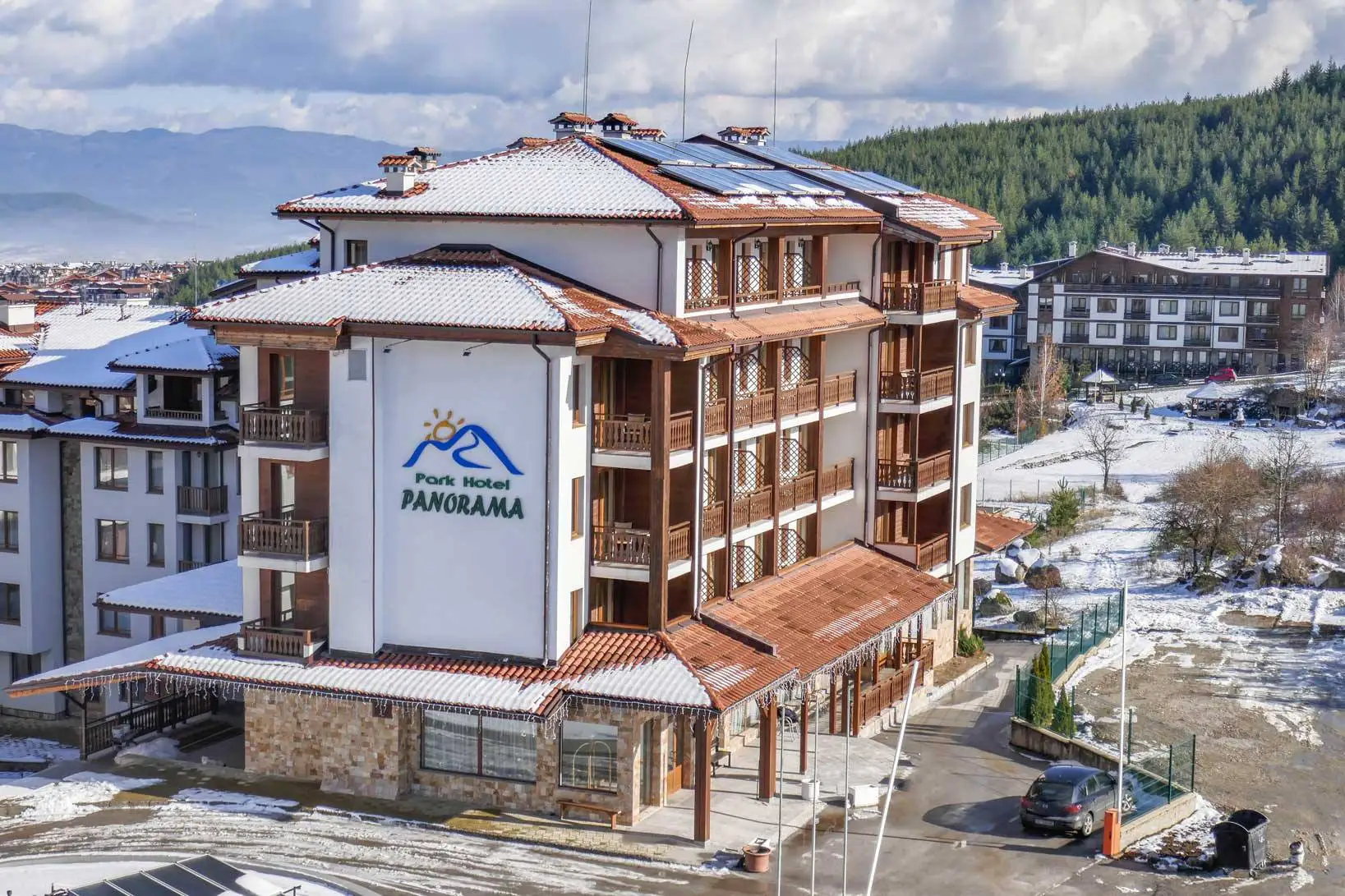 Хотелът от въздуха през зимата — надписът Park Hotel Panorama на фасадата, Банско и планината зад него